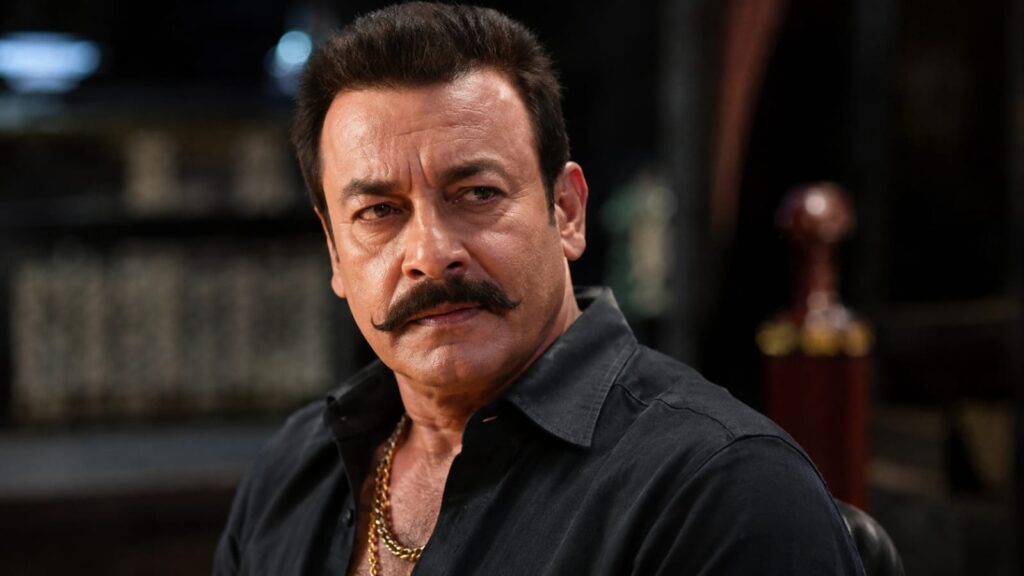 Alt Text Veteran actor Pradeep Rawat smiling in a black shirt during a portrait session.



